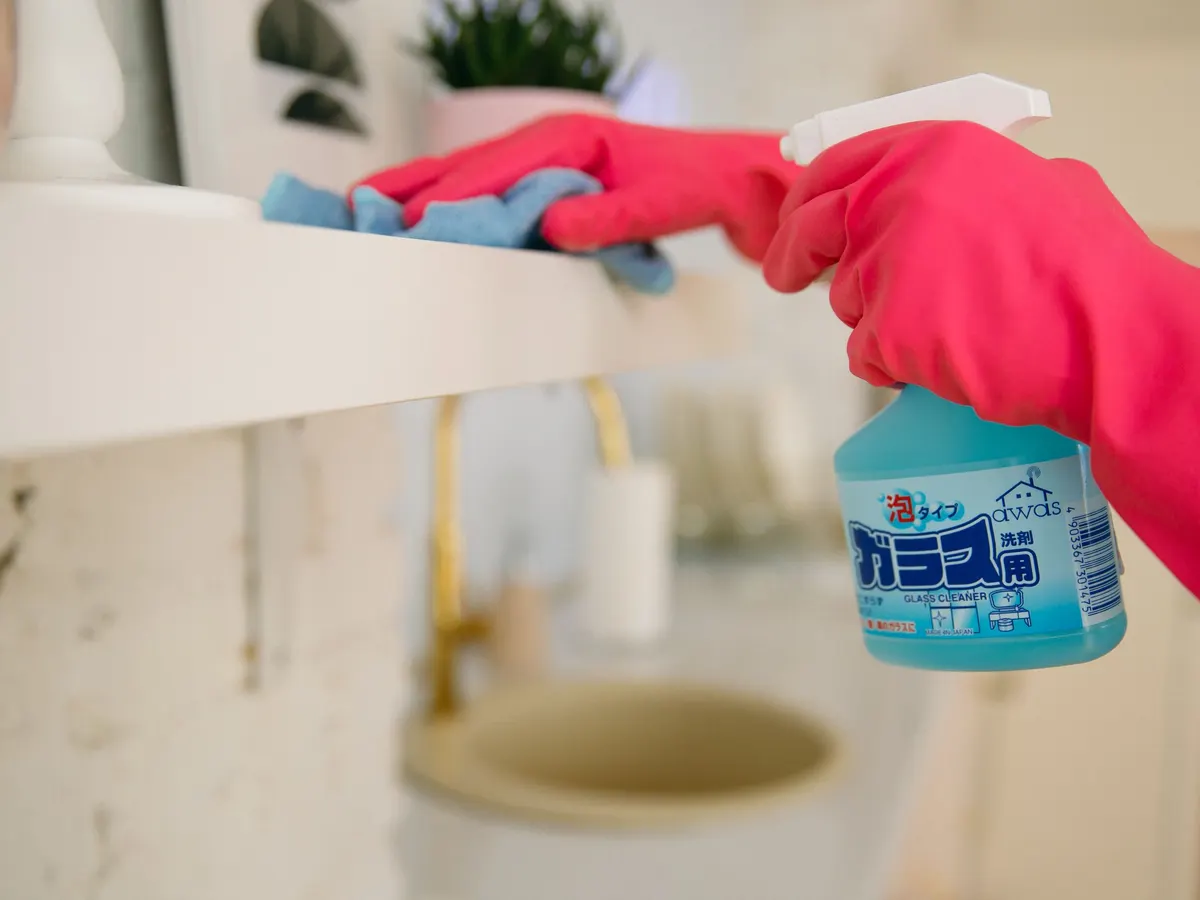 Gloved hand spraying a cleaner onto a surface